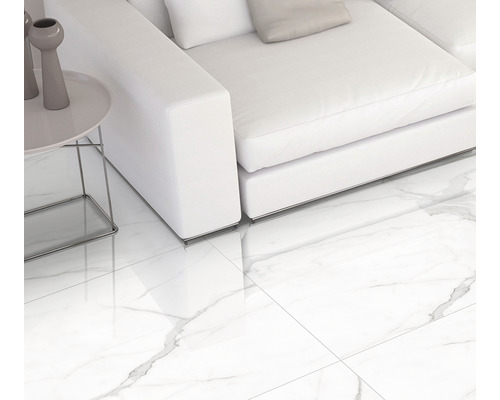 Cameră de zi luminoasă cu gresie albă cu aspect de marmură, canapea și măsuță laterală.