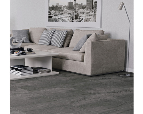 Living cu gresie gri, canapea, masă și lampă de podea