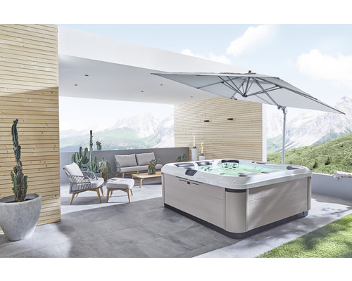 Cadă cu hidromasaj pe o terasă cu mobilier de grădină și umbrelă de soare