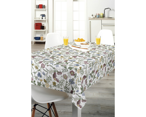 Masa de sufragerie aranjată cu o față de masă cu model floral într-o bucătărie luminoasă.