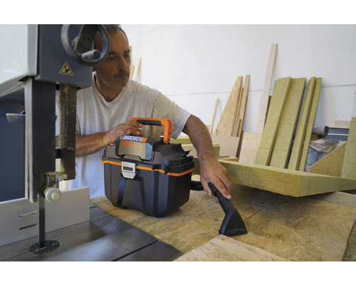 Artizan folosind un aspirator umed-uscat pe un banc de lucru cu fierăstrău cu bandă și resturi de lemn