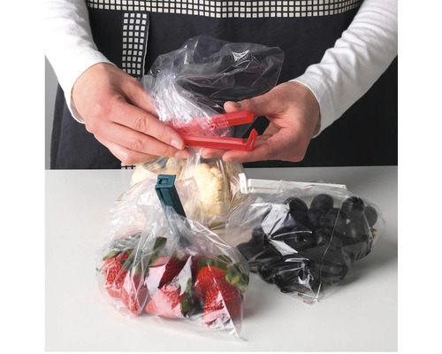 Mâini care închid pungi de plastic cu cleme de conservare