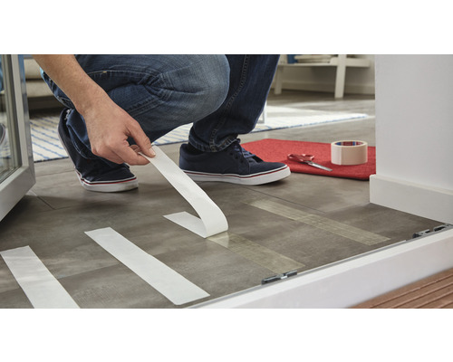 Persoană care lipește bandă adezivă pe podea