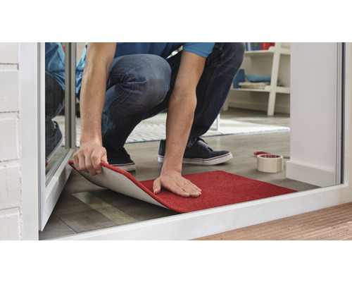 Persoană care instalează o covorașă roșie de interior