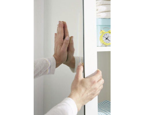 O persoană fixează o oglindă pe un dulap