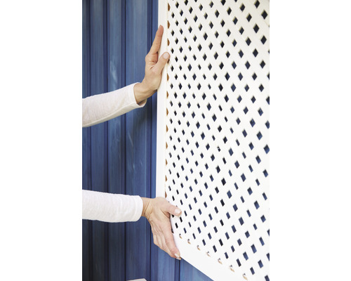 Persoană care montează un grilaj alb de acoperire a radiatorului cu model în romburi