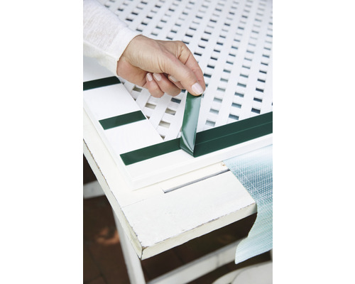 Persoană care fixează o mulură decorativă pe un element de grilaj