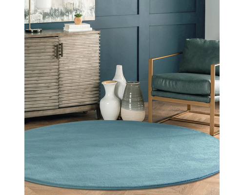 Scenă de sufragerie cu covor albastru rotund, comodă, scaun și vaze decorative