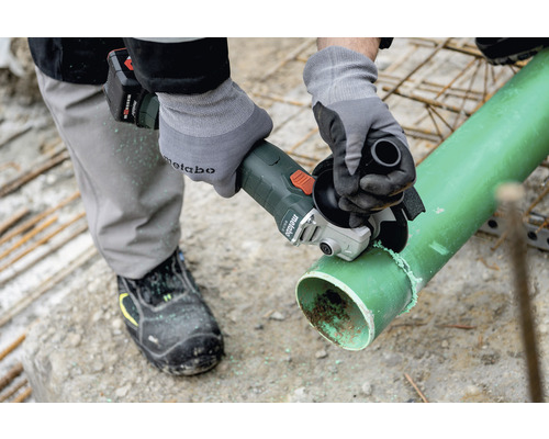 O persoană taie o țeavă cu o polizor unghiular fără fir.