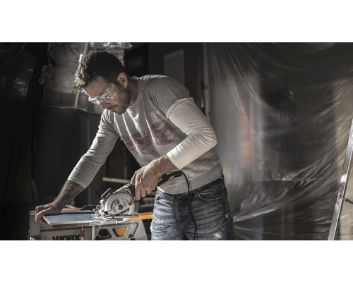 Bărbat cu ochelari de protecție tăind o scândură cu un ferăstrău circular Worx