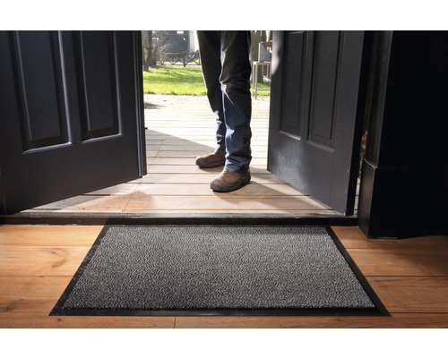 Covoraș de intrare în fața unei uși de intrare deschise pe o podea de lemn