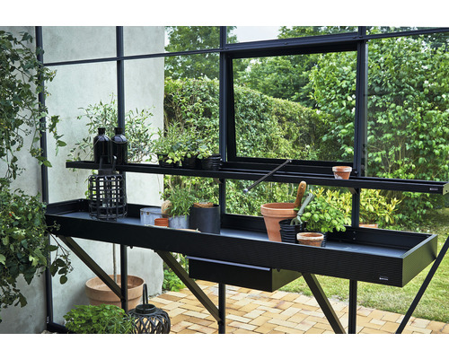 Măsuță de grădină cu plante și accesorii de grădină într-o seră