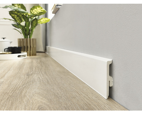 Prim-plan cu o plintă albă pe un perete, montată pe o podea de lemn.