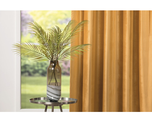 Palmier artificial decorativ în vază pe o măsuță laterală în fața unei perdele