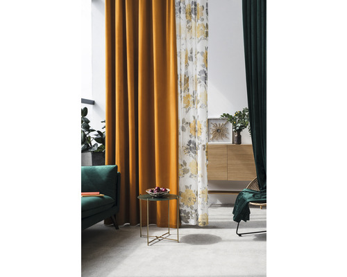 Cameră de zi cu perdele în galben, alb cu model floral și verde, o canapea verde, o măsuță laterală cu un bol cu fructe și un bufet.