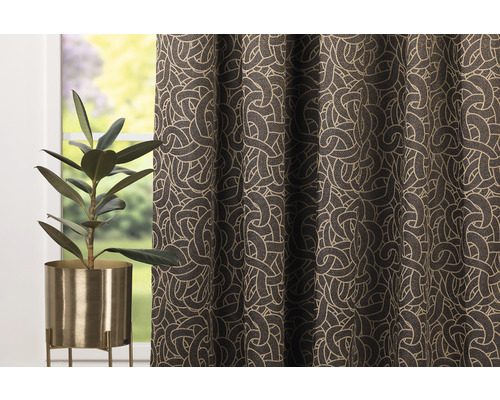 Cortină decorativă cu model spiralat și plantă de interior în ghiveci auriu.