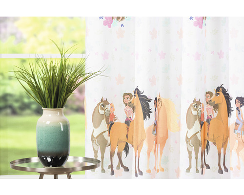 Cortină decorativă cu motive de cai și fete în camera copilului, completată de o plantă artificială pe o masă.