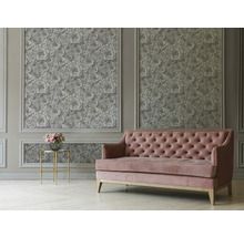 Cameră de zi cu tapet floral, canapea și măsuță laterală.