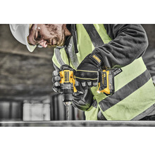 Un muncitor în construcții cu cască de protecție și vestă de siguranță găurește metal cu o bormașină DeWalt.