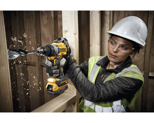 Femeie care face o gaură într-o scândură de lemn cu o șurubelniță cu acumulator