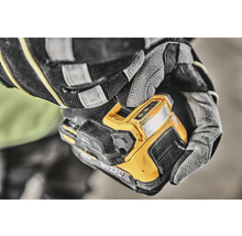 Un muncitor cu mănuși ține o lumină de lucru fără fir.