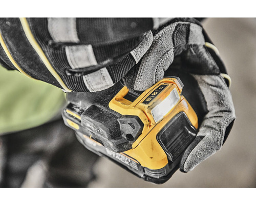 Un muncitor cu mănuși ține o lumină de lucru fără fir.