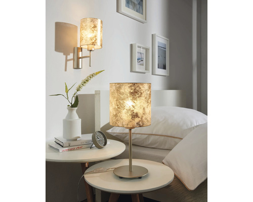 Două lămpi decorative într-un dormitor, una ca lampă de masă și una ca lampă de perete.