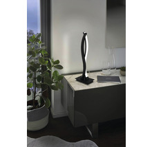 Lampă de masă cu LED modernă pe o noptieră cu blat de marmură lângă o plantă de interior.