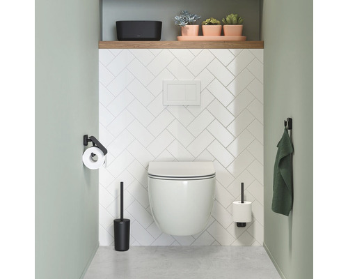 Baie modernă cu WC suspendat, perie WC, suport de hârtie igienică, prosop și plante