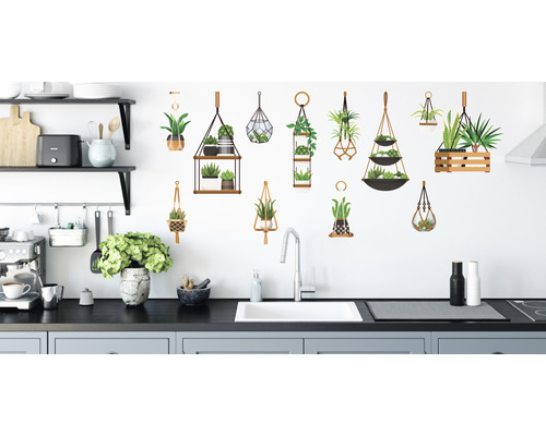 Scenă de bucătărie cu autocolante decorative cu plante pe un perete alb deasupra chiuvetei.
