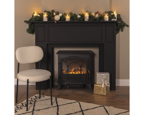 Șemineu decorativ cu decorațiuni, cadouri, fotoliu și covor într-o sufragerie