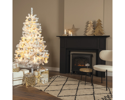 Brad artificial de Crăciun, acoperit cu zăpadă artificială, cu globuri și cadouri într-o sufragerie cu șemineu