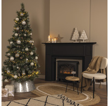 Brad împodobit lângă șemineu și scaun într-o sufragerie.