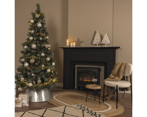 Brad împodobit lângă șemineu și scaun într-o sufragerie.