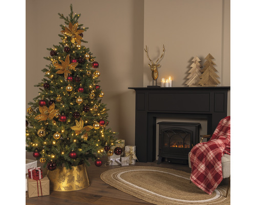 Brad festiv împodobit lângă un șemineu cu decorațiuni și cadouri