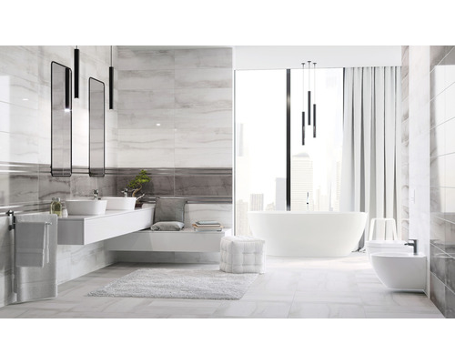 Baie luminoasă cu gresie cu aspect de marmură, lavoar, oglinzi, cadă și toaletă.