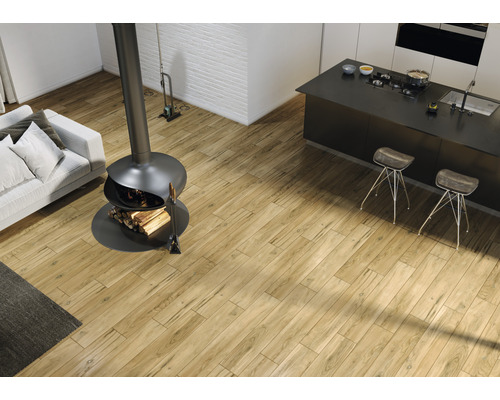 Cameră de zi luminoasă cu podea din lemn, șemineu, canapea și insulă de bucătărie.