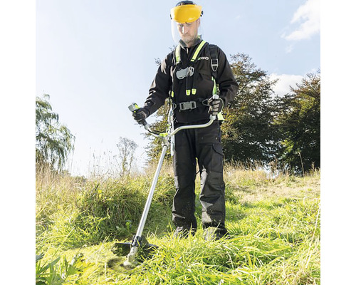 Bărbat cu vizieră și trimmer tăind gazonul