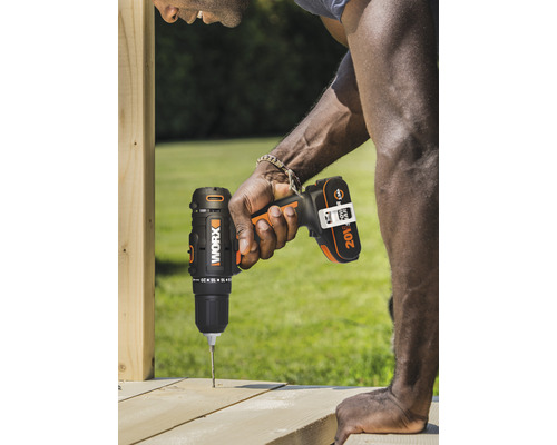 Un bărbat găurește o scândură de lemn cu o șurubelniță fără fir.