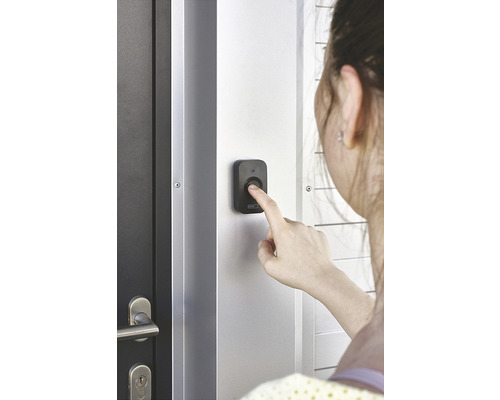 O persoană apasă un sonerie lângă o ușă.