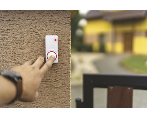 O persoană apasă un sonerie albă pe un perete