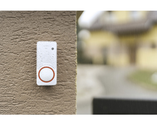 O sonerie albă cu un buton rotund este montată pe un perete.