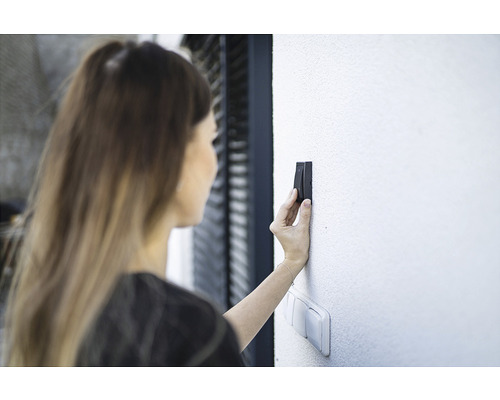 Femeie acționând un dispozitiv electronic de deschidere a ușii pe un perete