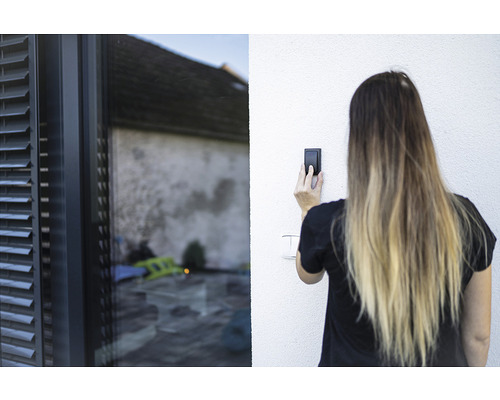 Femeie care operează un comutator lângă o fereastră cu jaluzele