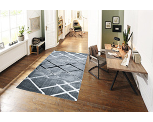 Cameră de zi cu covor, birou și podea din lemn.