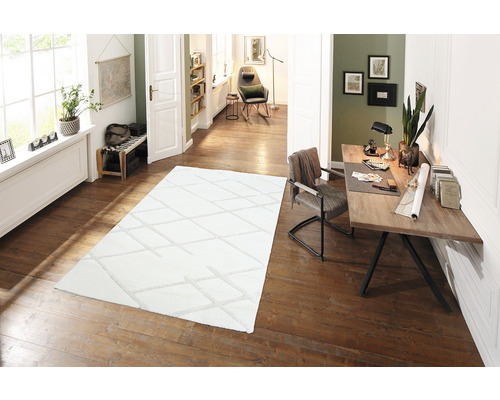 Cameră luminoasă cu covor, birou și scaun pe podea de lemn