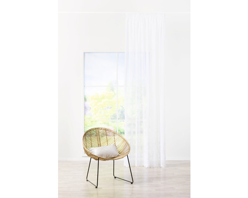 Cameră luminoasă cu scaun din ratan, pernă și perdea albă în fața unei ferestre