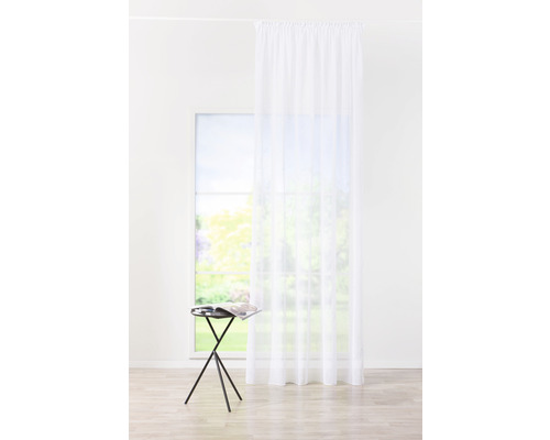 Vedere într-o cameră luminoasă cu o draperie albă transparentă în fața unei ferestre