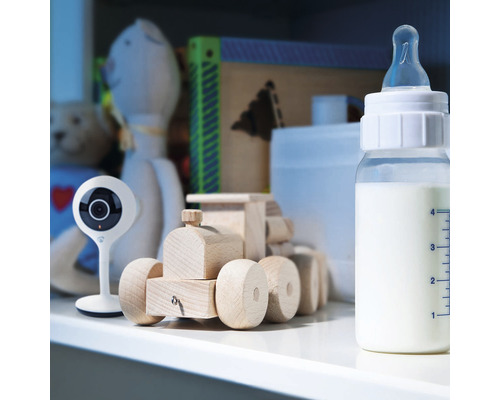 Biberon, baby monitor și jucării din lemn în camera copilului