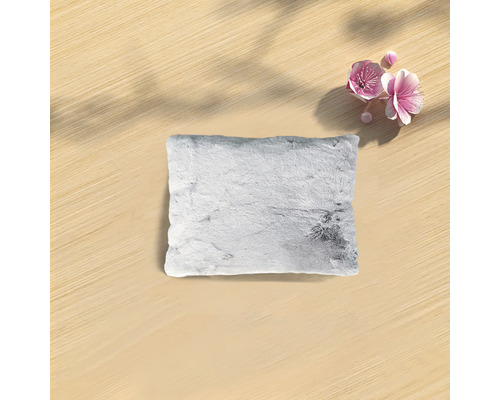 Pernă decorativă cu textură de blană pe o masă